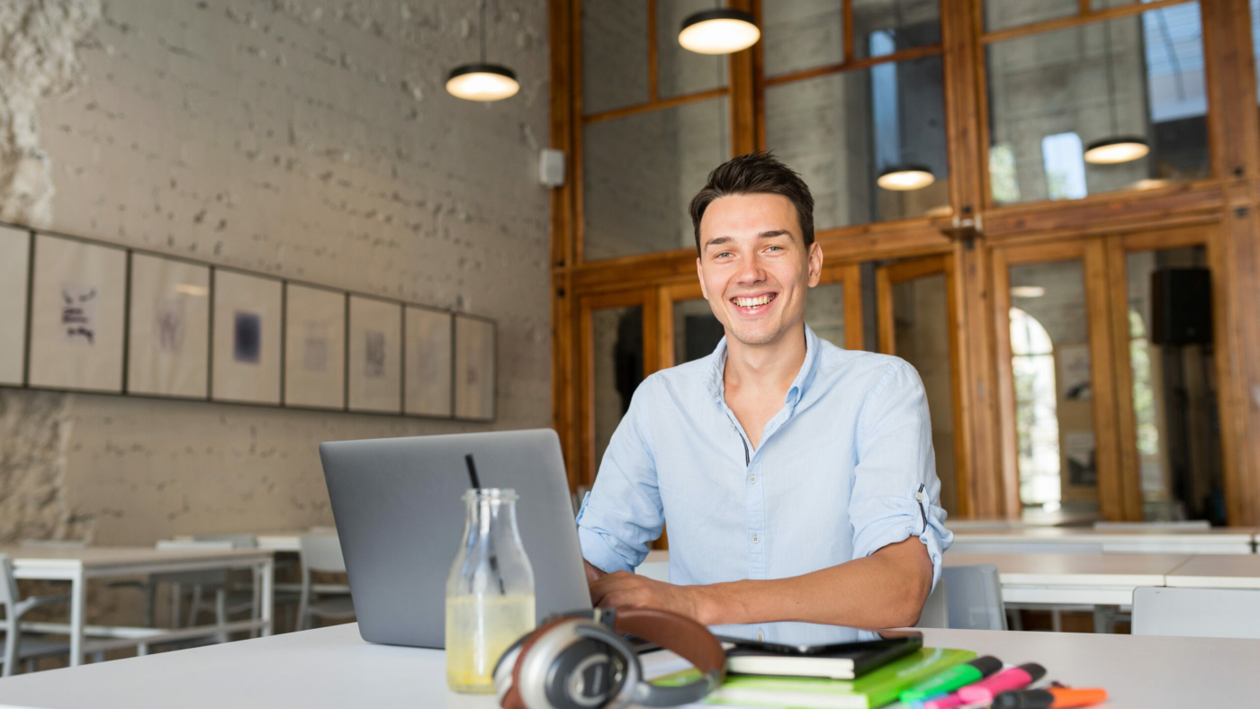 modern young confident man working on laptop, sitting in co-working office, freelance job, typing