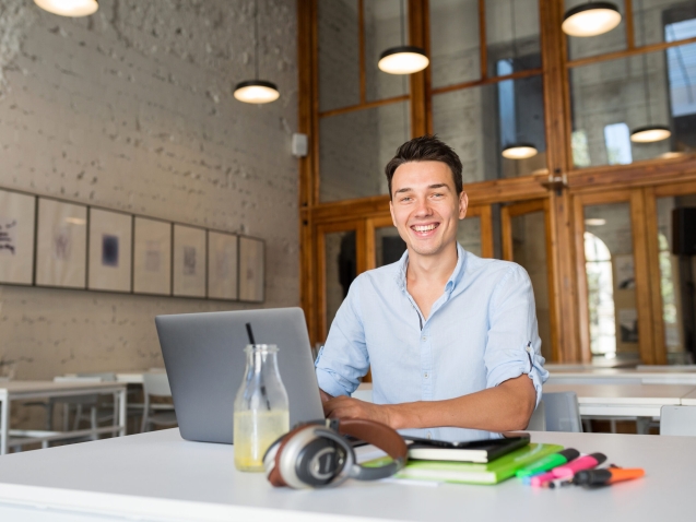 modern young confident man working on laptop, sitting in co-working office, freelance job, typing